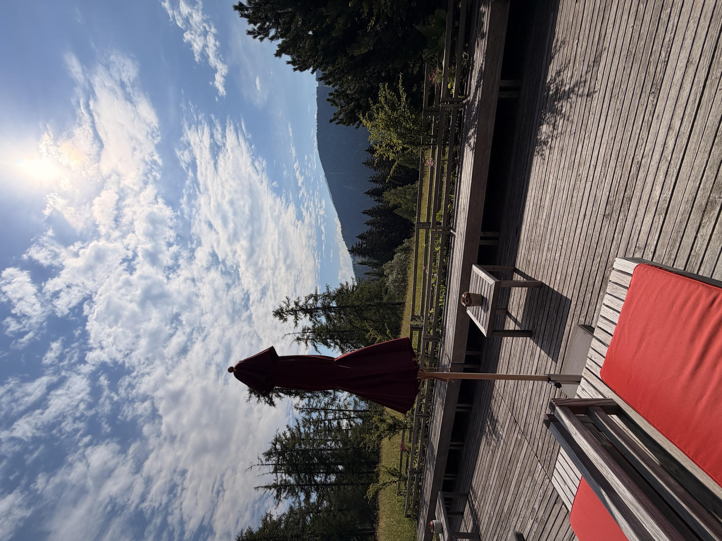 Quiet wooden terrace at Vigilius Mountain Resort overlooking the forest at golden hour